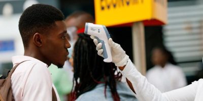 A health worker checks the temperature of a traveller as part of the coronavirus screening procedure at the Kotoka International Airport in Accra,